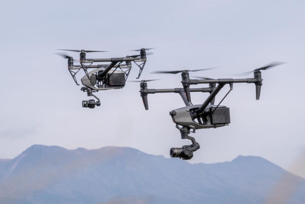 阿蘇山を背景にDJI INSPIRE 3と2が2機編隊飛行する様子。